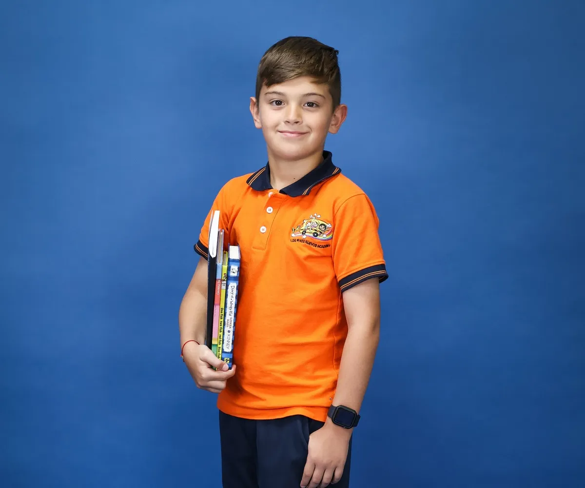 Estudiante de tercer grado de pie, con sus libros bajo el brazo, listo para volar